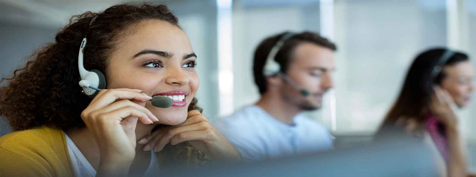 2 women and a man wearing headsets in a call center