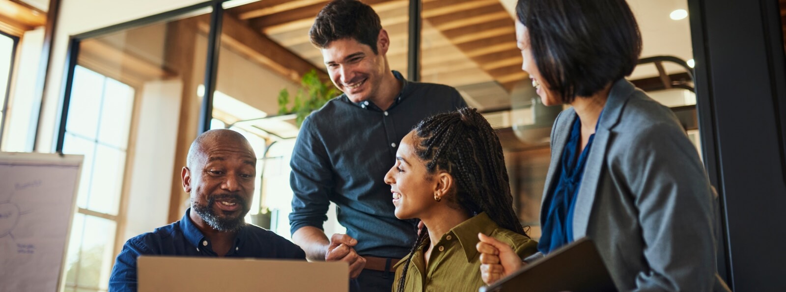 diverse group of office workers talking around a laptop