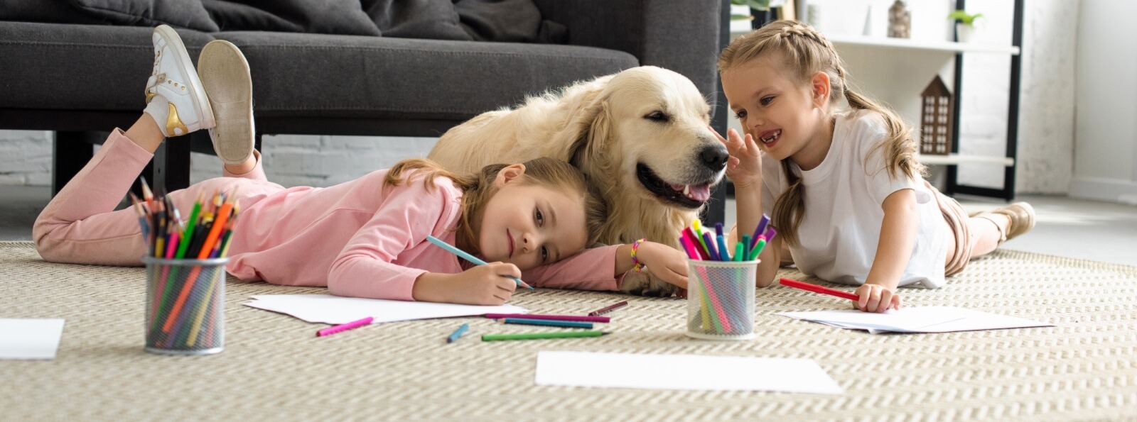 two young girls and family dog playing on the floor in a living room