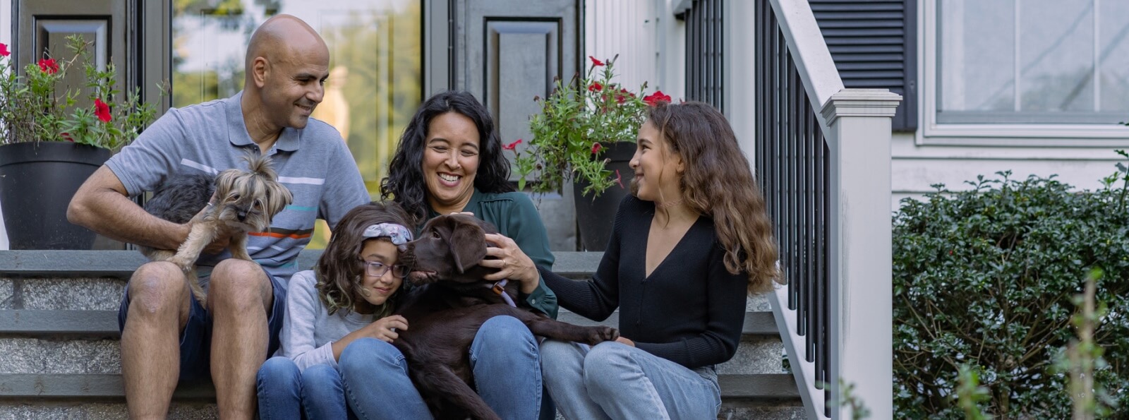 young family and puppy sitting outside on house stairs