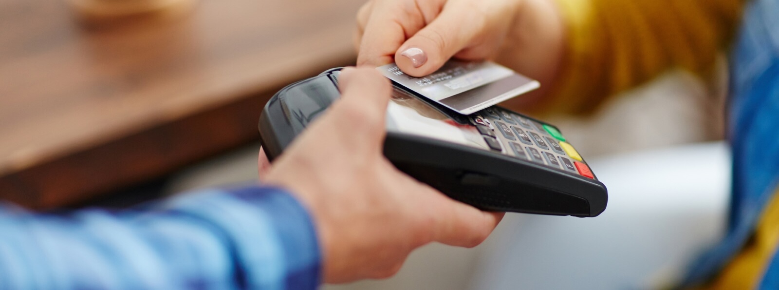 close-up of hand tapping a credit card on a card payment machine